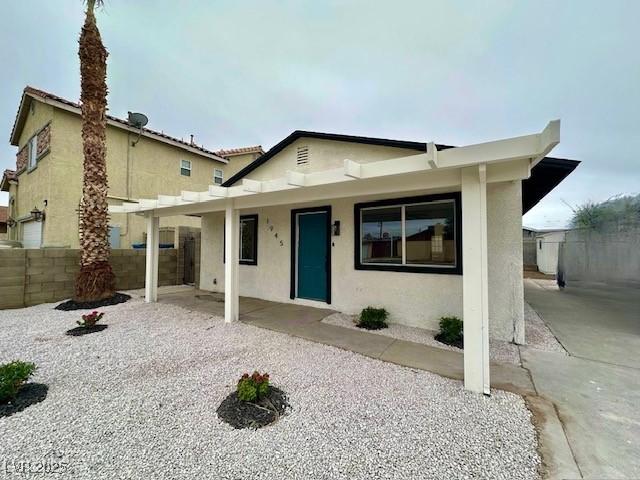 view of front of home with a patio, fence, and stucco siding