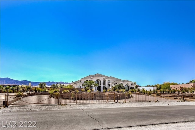 view of front of property with a fenced front yard, a mountain view, and a gate