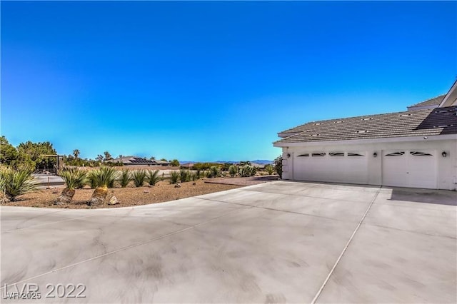 view of home's exterior featuring stucco siding, concrete driveway, and a tiled roof