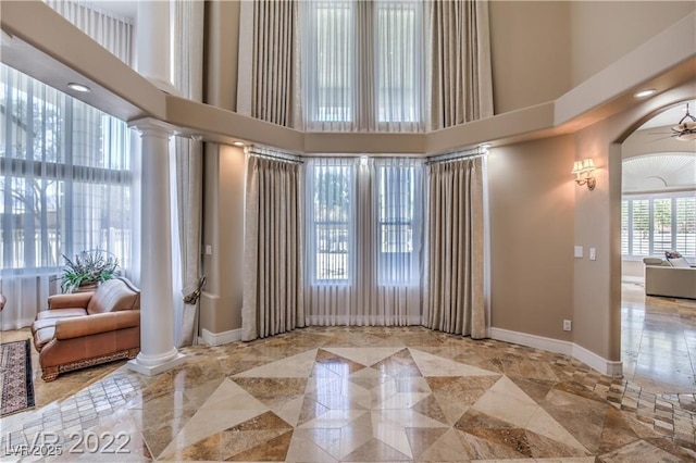 spare room featuring decorative columns, baseboards, and ceiling fan