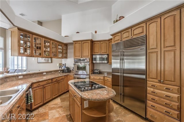 kitchen featuring visible vents, glass insert cabinets, brown cabinetry, stainless steel appliances, and open shelves