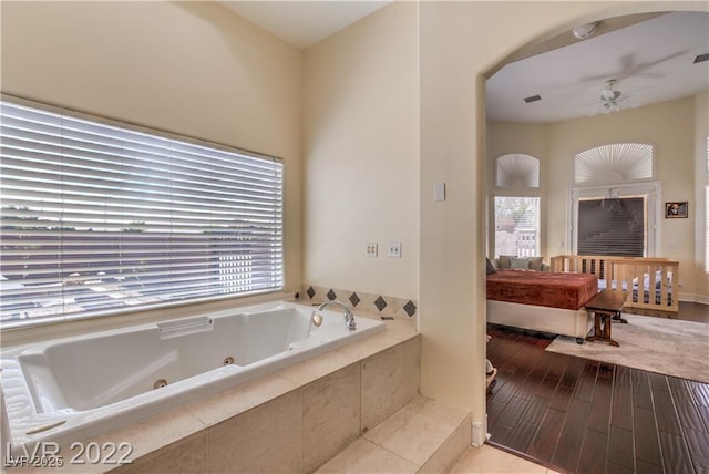 bathroom with visible vents, a jetted tub, a ceiling fan, and wood finished floors