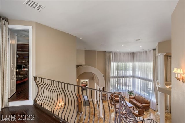 hall featuring wood finished floors, arched walkways, and visible vents