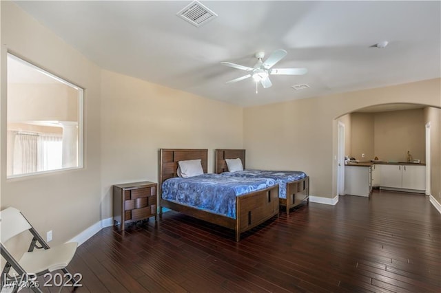 bedroom featuring visible vents, a ceiling fan, arched walkways, wood-type flooring, and baseboards