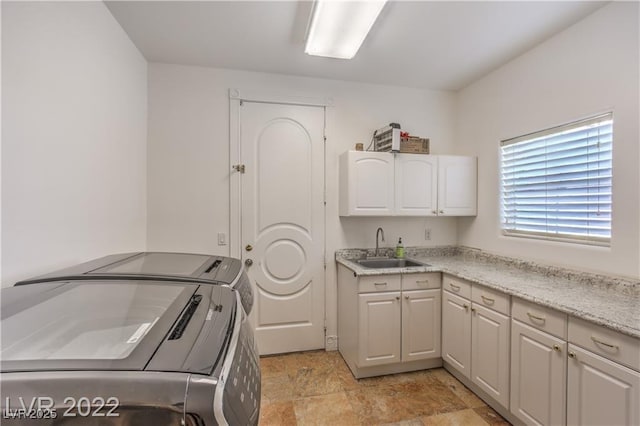 laundry area featuring cabinet space, stone finish floor, separate washer and dryer, and a sink