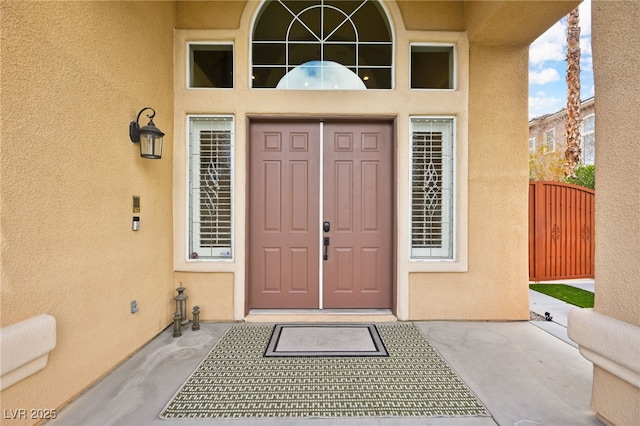 view of exterior entry featuring stucco siding and a gate