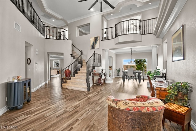 foyer with visible vents, crown molding, ceiling fan, decorative columns, and wood finished floors