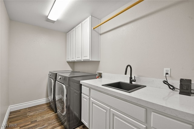 laundry room featuring washer and clothes dryer, a sink, dark wood-style floors, cabinet space, and baseboards