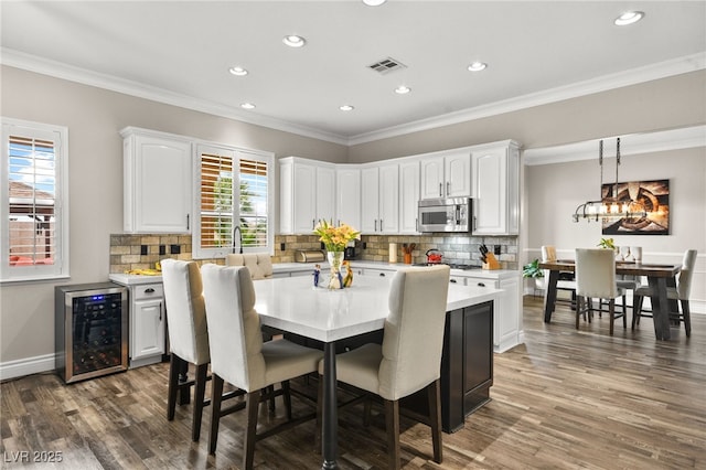 dining area with wood finished floors, visible vents, baseboards, wine cooler, and crown molding