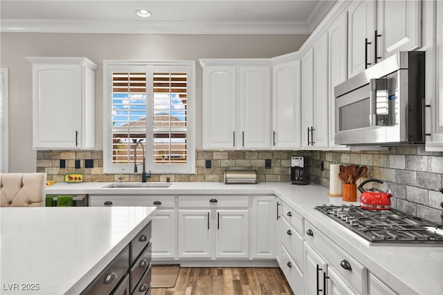 kitchen with white cabinetry, stainless steel appliances, light countertops, and a sink