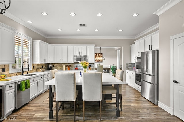 kitchen with a breakfast bar area, a kitchen island, a sink, stainless steel appliances, and white cabinetry