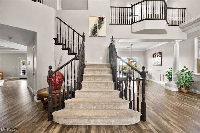 staircase featuring a wealth of natural light, crown molding, a high ceiling, and wood finished floors