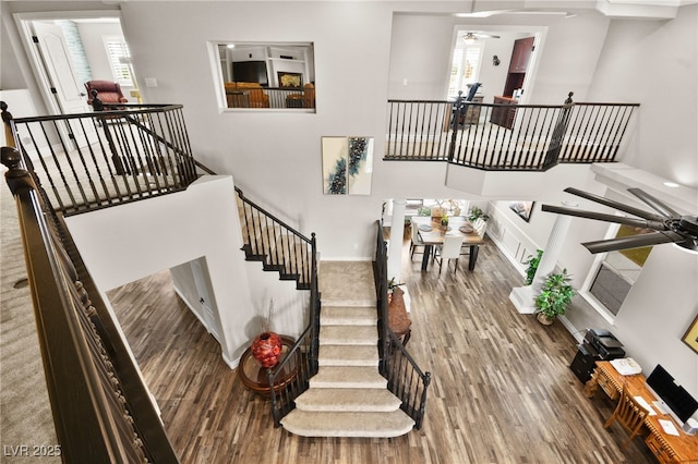 staircase with wood finished floors, a ceiling fan, baseboards, and a wealth of natural light