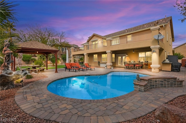 pool at dusk with a gazebo, an outdoor pool, outdoor dining area, and a patio