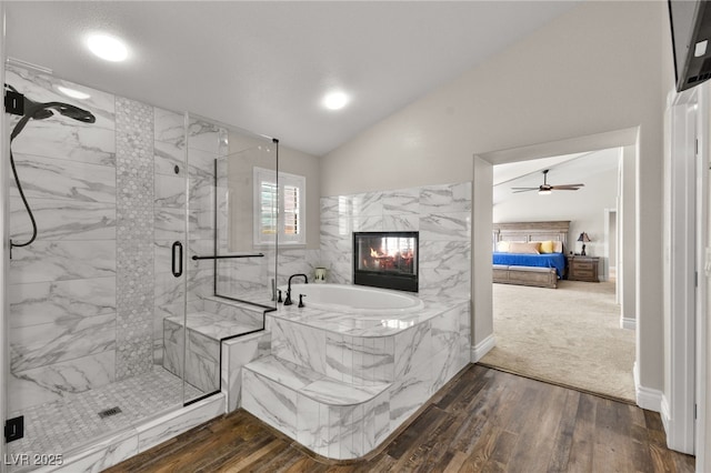 full bathroom featuring a marble finish shower, lofted ceiling, a premium fireplace, wood finished floors, and a bath