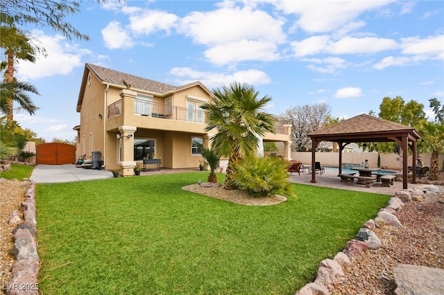 rear view of house with fence, a gazebo, stucco siding, a balcony, and a patio