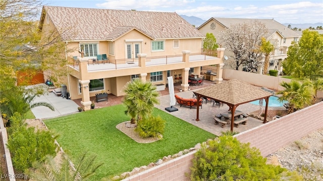 back of property with a balcony, a patio area, a fenced backyard, and stucco siding