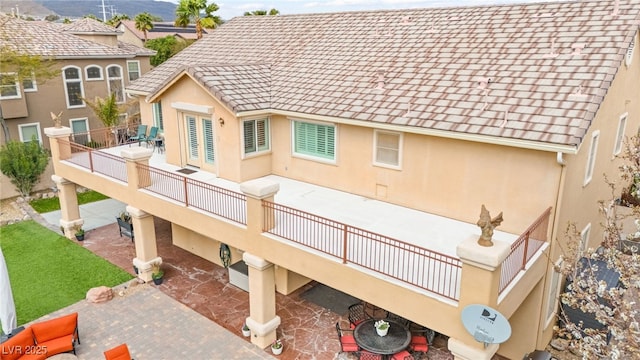 exterior space featuring a shingled roof, a downspout, gutters, and stucco siding