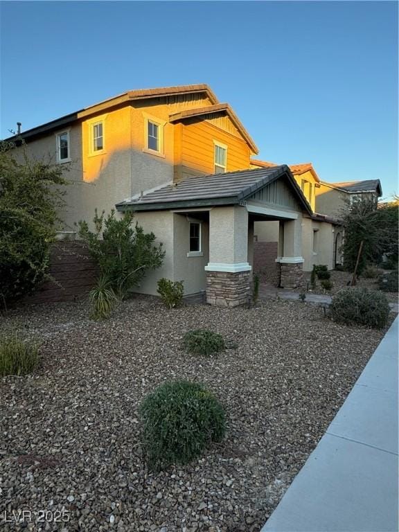 exterior space featuring stone siding, stucco siding, and a tiled roof