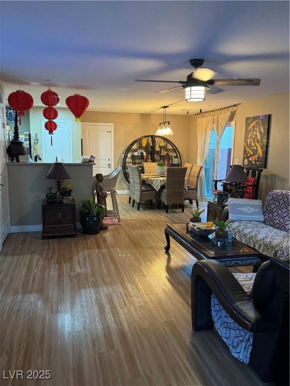 living room featuring baseboards, wood finished floors, and a ceiling fan