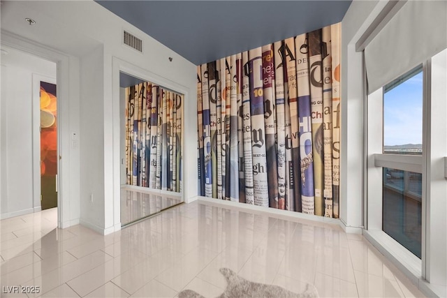 spare room featuring tile patterned floors, visible vents, and baseboards