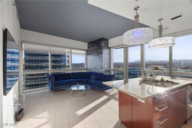 kitchen featuring visible vents, light stone countertops, hanging light fixtures, plenty of natural light, and a sink