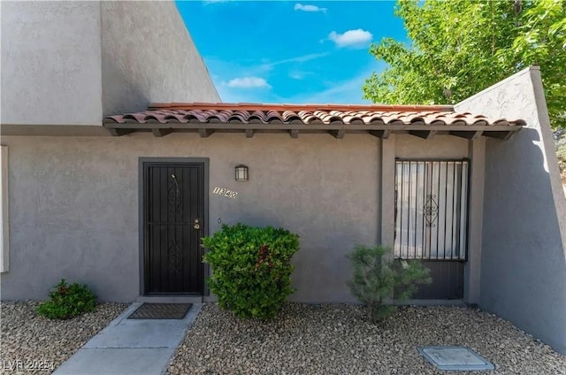 property entrance with a tile roof and stucco siding