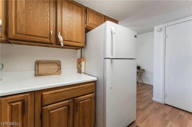 kitchen featuring brown cabinets, light wood-style floors, light countertops, and freestanding refrigerator