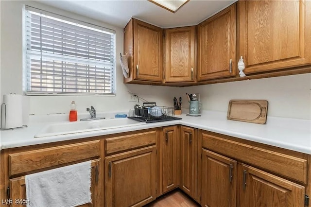 kitchen featuring light countertops, brown cabinetry, and a sink