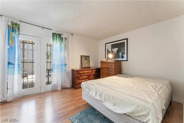 bedroom with a textured ceiling, access to exterior, and light wood finished floors