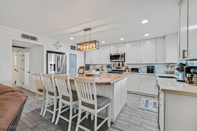 kitchen featuring visible vents, light countertops, appliances with stainless steel finishes, white cabinets, and a sink