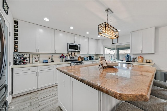 kitchen featuring a center island, white cabinetry, stainless steel appliances, and a kitchen breakfast bar