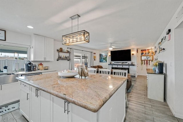 kitchen with a wealth of natural light, a kitchen island, ceiling fan, and white cabinetry