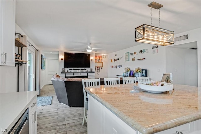 kitchen featuring a ceiling fan, visible vents, wood finish floors, white cabinets, and open floor plan