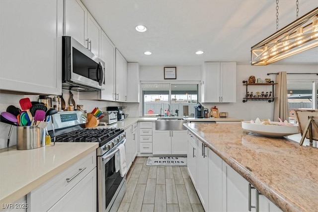 kitchen featuring wood tiled floor, recessed lighting, white cabinets, stainless steel appliances, and a sink