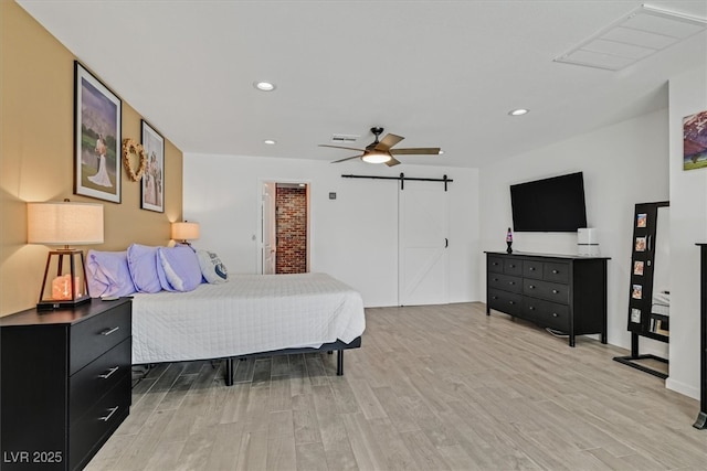 bedroom featuring a ceiling fan, visible vents, recessed lighting, light wood-style floors, and a barn door