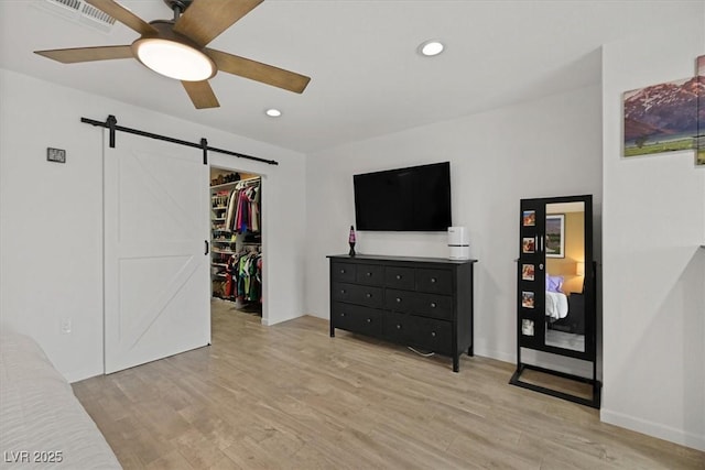 bedroom featuring visible vents, recessed lighting, light wood-style floors, a walk in closet, and a barn door