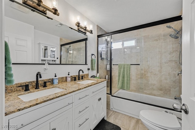 full bath featuring a sink, enclosed tub / shower combo, toilet, and double vanity