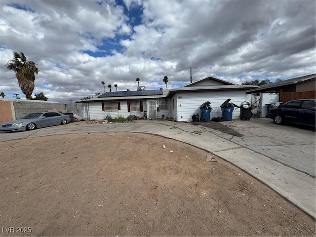 single story home featuring roof mounted solar panels and driveway