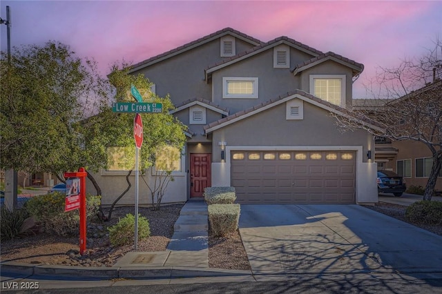 traditional home featuring a tile roof, stucco siding, concrete driveway, and a garage