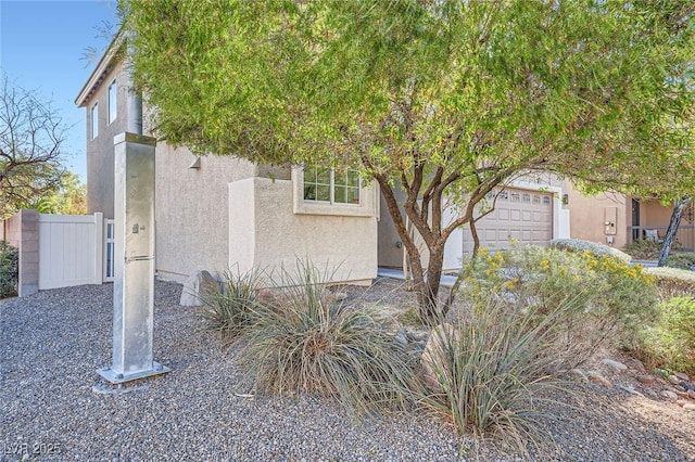 view of front facade with an attached garage, fence, and stucco siding