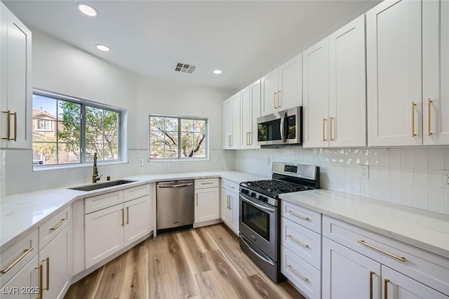 kitchen featuring visible vents, a sink, decorative backsplash, white cabinets, and appliances with stainless steel finishes