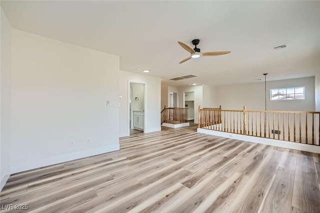 empty room featuring light wood-style floors, visible vents, and ceiling fan