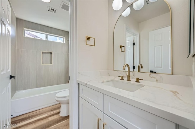 full bathroom with visible vents, toilet, shower / bathtub combination, wood finished floors, and vanity