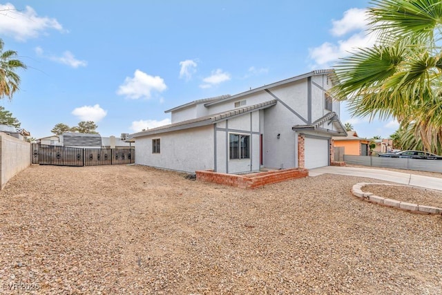 back of house featuring stucco siding, a gate, fence, concrete driveway, and an attached garage