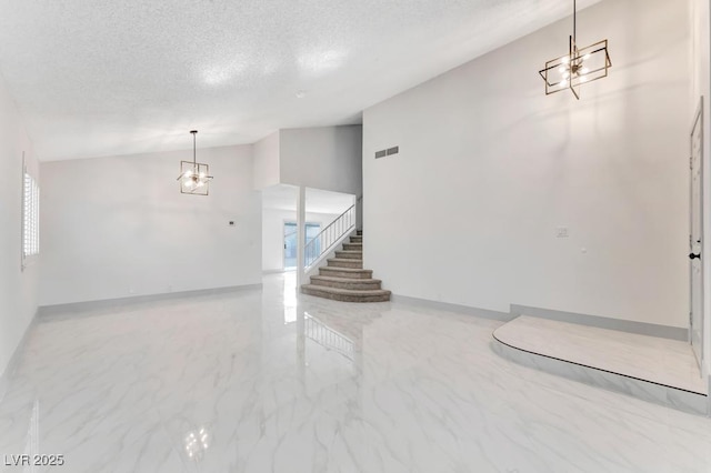 unfurnished living room with visible vents, vaulted ceiling, a textured ceiling, marble finish floor, and a chandelier