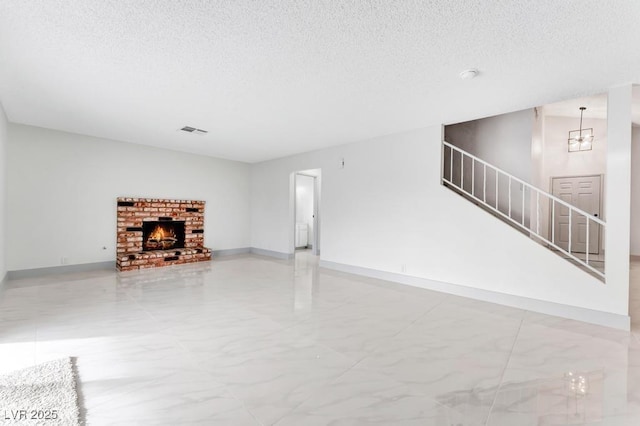 unfurnished living room with visible vents, a textured ceiling, marble finish floor, and stairs