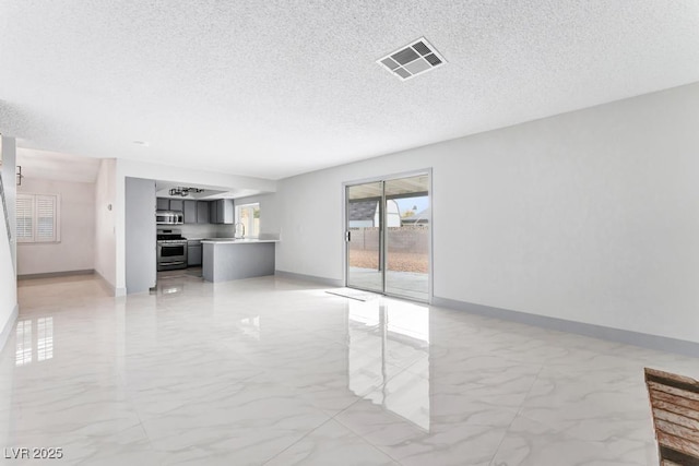 unfurnished living room featuring visible vents, baseboards, a textured ceiling, and marble finish floor