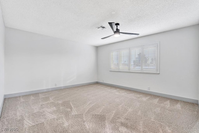 carpeted spare room with a textured ceiling, a ceiling fan, visible vents, and baseboards