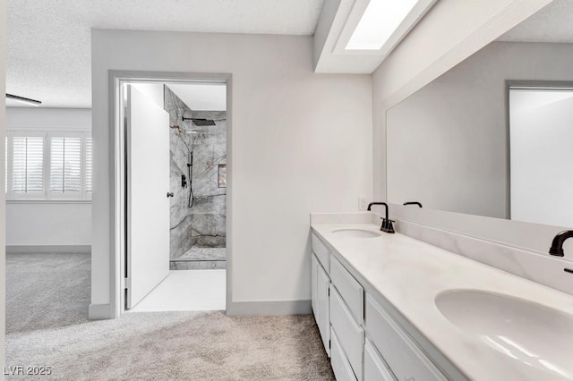 bathroom with baseboards, double vanity, a stall shower, a sink, and a textured ceiling